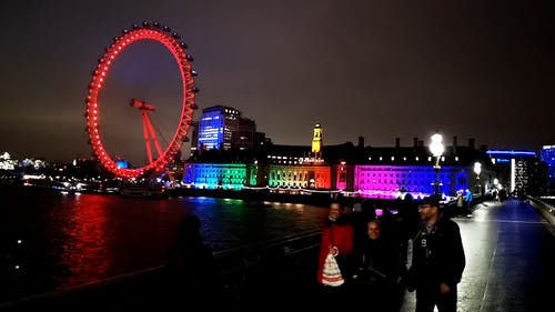 霓虹灯在伦敦眼观察轮后面的建筑物上显示 · 免费素材视频