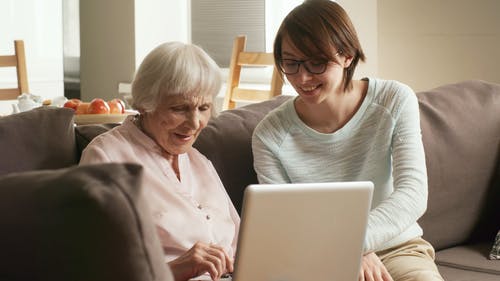 一个年轻的女人，教一名老妇如何使用一台笔记本电脑 · 免费素材视频
