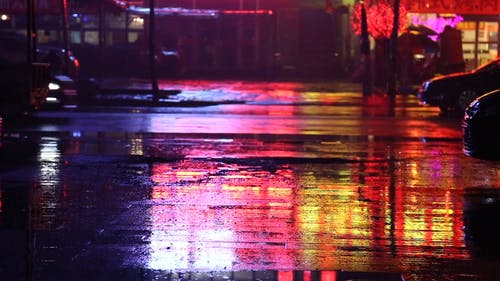 两个女人用伞站在雨夜空荡荡的街道中间 · 免费素材视频