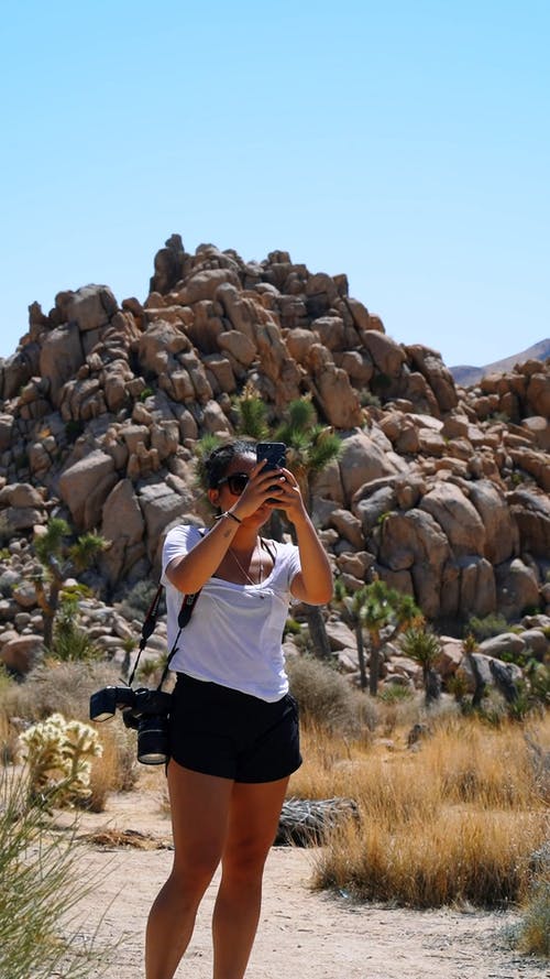 一个女人用她的智能手机拍摄沙漠周围的完整镜头 · 免费素材视频