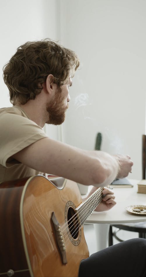 弹吉他时吸烟的人 · 免费素材视频