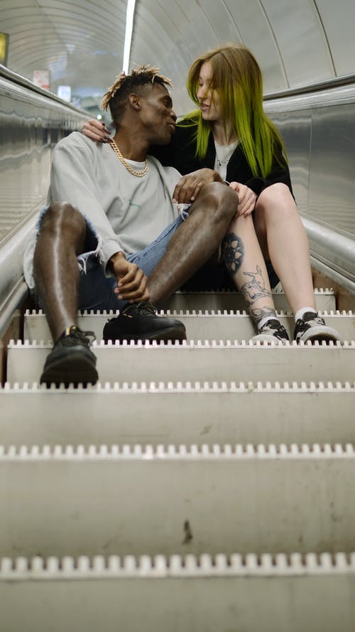 一对夫妇坐在自动扶梯的台阶上 · 免费素材视频