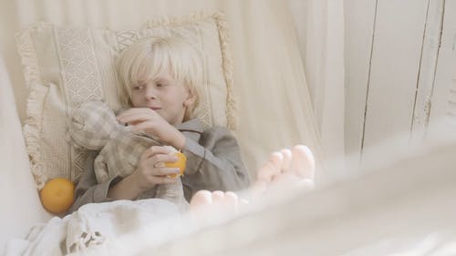 一个男孩躺在吊床上拥抱橙色的玩具时拥有橙色水果 · 免费素材视频
