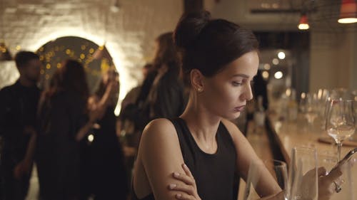 一个女人坐在酒吧与一群人在后面跳舞 · 免费素材视频
