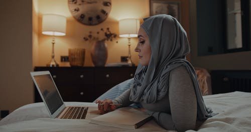盖头看着笔记本电脑，做笔记的女人 · 免费素材视频