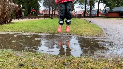 一个孩子在地面上的水残留物上跳来跳去 · 免费素材视频