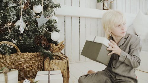 一个男孩检查圣诞树下面的礼物一盒 · 免费素材视频