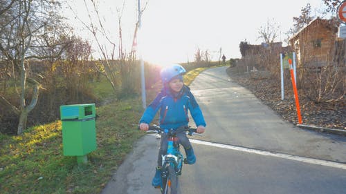 一个戴着头盔在街上骑自行车的孩子 · 免费素材视频