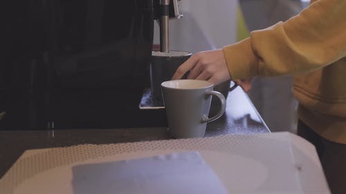 一个女人在等待她的杯子被点胶机装满 · 免费素材视频