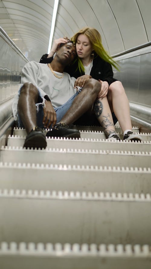 一对夫妇坐在向上的自动扶梯的台阶上 · 免费素材视频