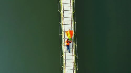 一名男子穿着垂悬窗帘躺在人行天桥上 · 免费素材视频