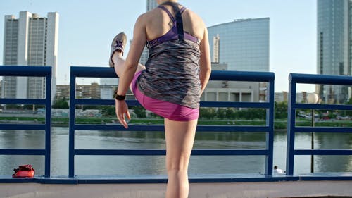 一个女人在栏杆上举起一条腿做伸展运动 · 免费素材视频
