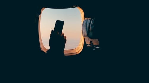 有靠窗座位的飞机乘客在飞行中使用他的手机 · 免费素材视频