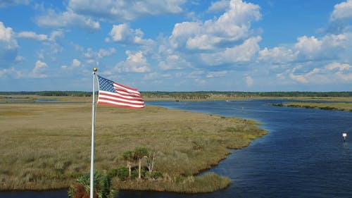 一面美国国旗摇杆在河沼泽 · 免费素材视频