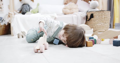 一个孩子在游戏室的地板上玩木制玩具 · 免费素材视频