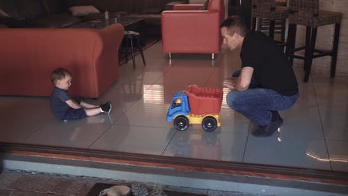 父亲和儿子通过向前和向后推塑料玩具卡车玩 · 免费素材视频
