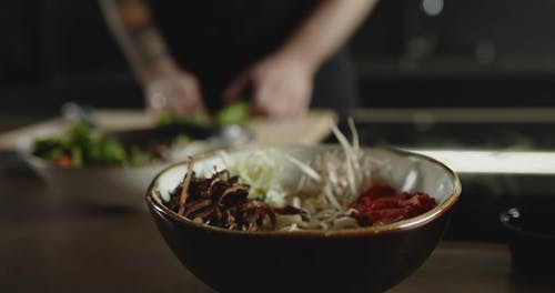 一个人用白菜蔬菜在面条汤碗里加浇头 · 免费素材视频