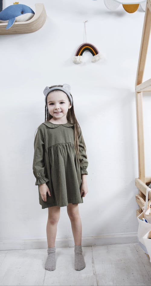 一个女孩站在游戏室，高兴地展示她的衣服 · 免费素材视频