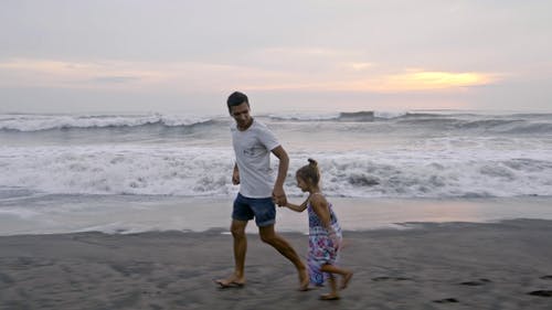 一位父亲和他的女儿在沙滩上奔跑 · 免费素材视频