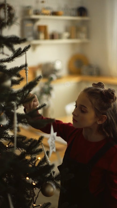 固定在圣诞节装饰品装饰圣诞树上的女孩 · 免费素材视频