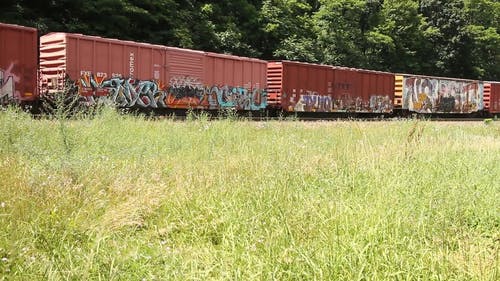 带有涂鸦艺术的货运火车在铁路上行驶的货运集装箱上 · 免费素材视频