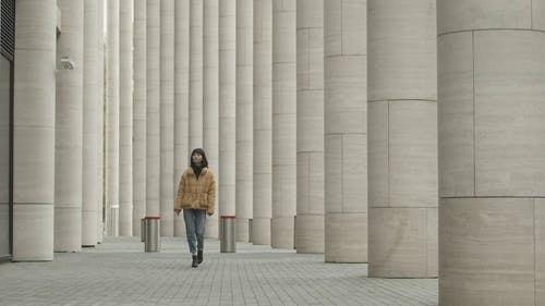 一个女人走在建筑物之间的支柱之间 · 免费素材视频
