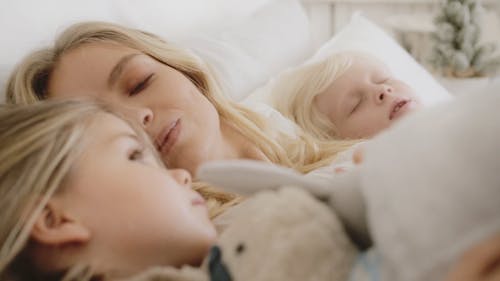 一位母亲带着两个孩子在一起躺在床上的时刻 · 免费素材视频
