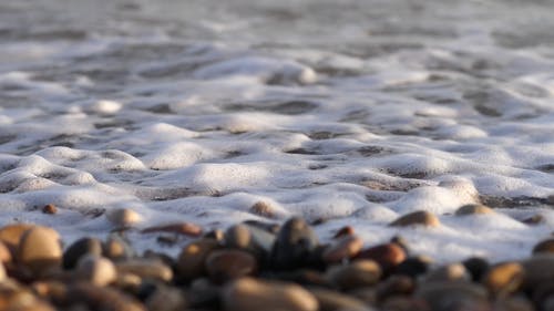 海浪亲吻堆积在海边的鹅卵石 · 免费素材视频