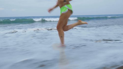 一个女人赤脚跑在沙滩海岸线上 · 免费素材视频