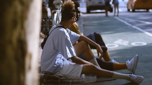 两名男子坐在人行道上互相交谈 · 免费素材视频