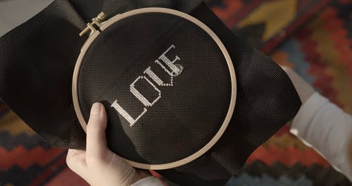 一个人十字绣在黑布上的单词“爱” · 免费素材视频