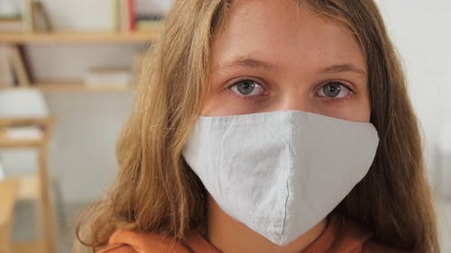 一个年轻的女学生在学校戴口罩 · 免费素材视频