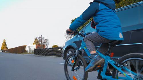 一个小男孩在附近的街道上骑自行车 · 免费素材视频
