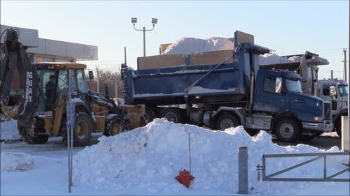 看着卡车装载机卸下一包雪 · 免费素材视频