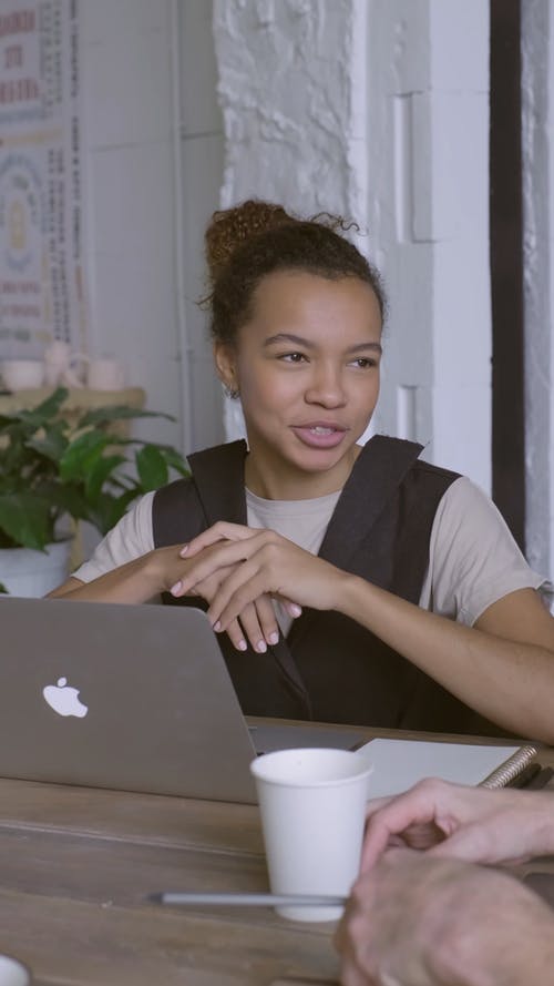 一个女人坐在膝上电脑与周围的其他人说话 · 免费素材视频