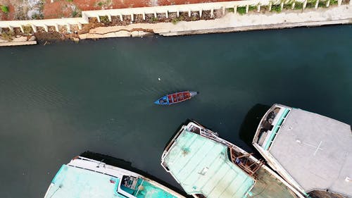小型机动船驶过港口的大型渔船 · 免费素材视频