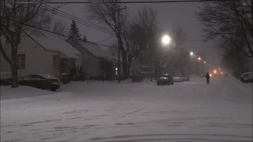 一个穿着黑色冬天的衣服的人在被雪覆盖的道路上行走 · 免费素材视频