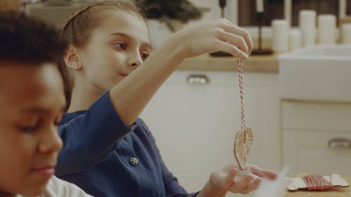 一个女孩显示一个饼干挂在一根绳子上 · 免费素材视频