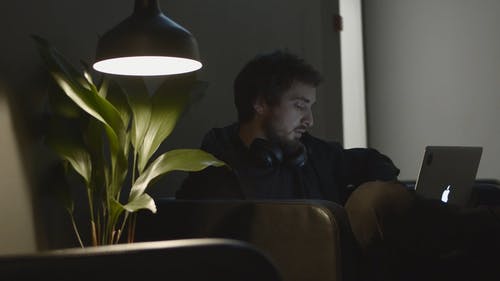 一个人在笔记本电脑上工作时戴上耳机 · 免费素材视频