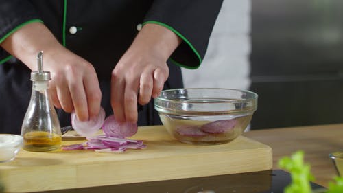 一个人用橄榄油在一个水晶碗上扔洋葱片 · 免费素材视频