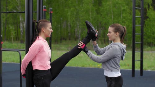 一个女人在协助另一个女人抬起她的腿来充分伸展 · 免费素材视频