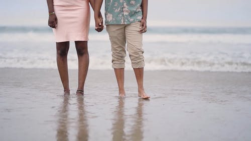 一对情侣在海滩散步，手牵着手 · 免费素材视频