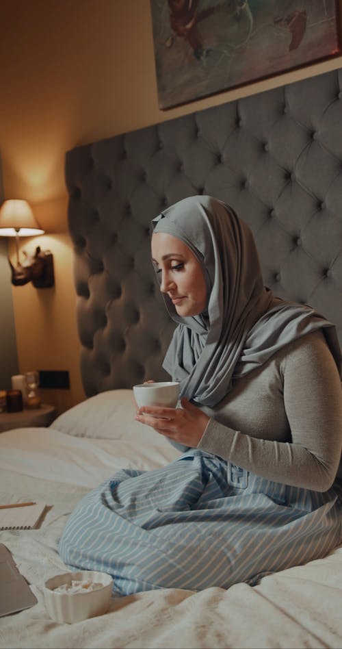 一个女人使用一台笔记本电脑和在她的床上吃点心 · 免费素材视频