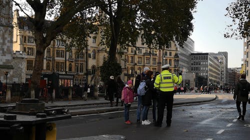 一个游客家庭正在向伦敦街的一名警察问路 · 免费素材视频