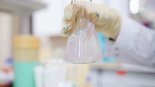 科学家在实验室内的玻璃烧瓶上混合液体 · 免费素材视频