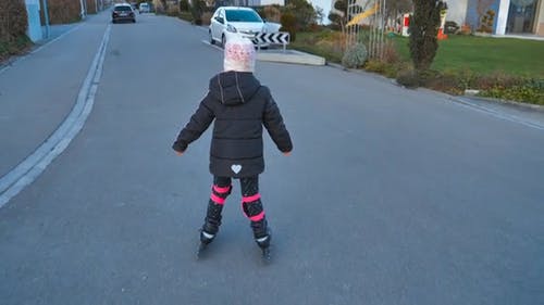 一个年轻的女孩，与她的旱冰鞋在开阔的住宅街道上练习 · 免费素材视频