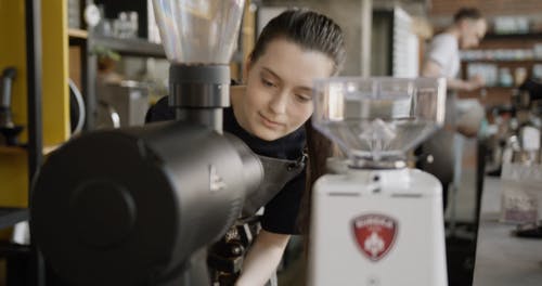 一位女咖啡师，闻到新鲜研磨的咖啡豆 · 免费素材视频