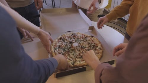 一群人在工作场所厨房里抢一片披萨 · 免费素材视频
