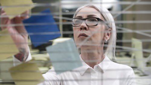 一个女人检查纸垫上的笔记粘到玻璃面板 · 免费素材视频