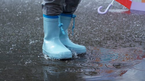 一个穿着防水靴的人踩在地面上的雨水残留物 · 免费素材视频